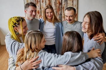 Группа пациентов реабилитационного центра держатся за руки